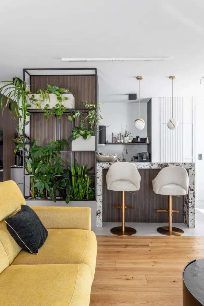 nowoczesny-salon-apartament-warszawa-kabaty-2 nowoczesny salon z kuchnią i wyspą, rośliny w zabudowie, jasne wnętrze z drewnianą podłogą